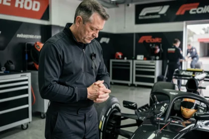 Mécanicien de Formule 1 en deuil dans le paddock avec un ruban de condoléances épinglé sur son uniforme