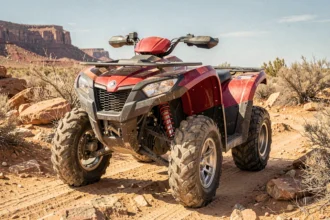Yamaha Raptor 700 garé sur une piste désertique rocailleuse, vue avant trois quarts basse mettant en valeur le châssis agressif et les pneus tout-terrain
